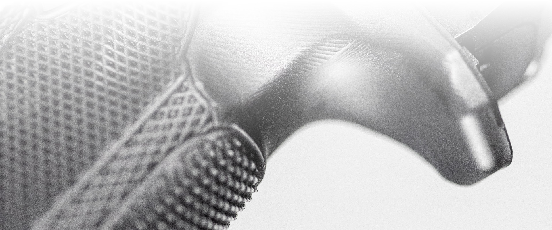 Close-up view of a modern handgun grip and beaver tail on a neutral background